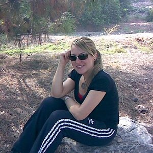 Adidas womans black pants with white stripes sitting sunglasses