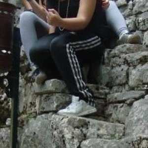 Adidas womans black pants with white stripes crouched rocks