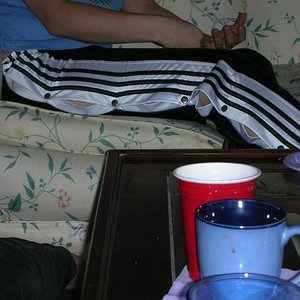 Adidas womans black pants large white stripes sitting side shot