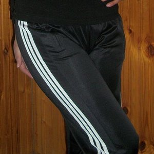 Adidas womans black sheen pants white stripes knee pose