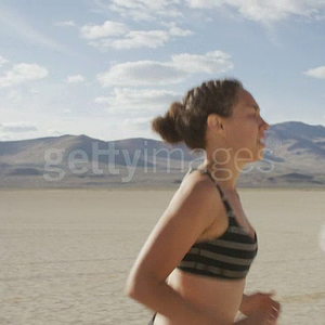 profile-shot-of-a-woman-running-through-the-dessert-video-id1023062670.mp4