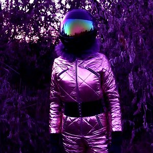 SYMBOLISM OF PERFECTION. Walking in golden shining ski overalls with hood + moto. helmet or gas mask