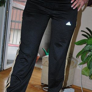 Adidas womens black pants gold stripe front leg pose