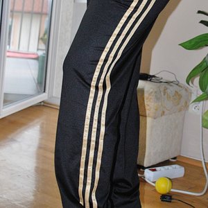 Adidas womens black pants gold stripe side leg pose